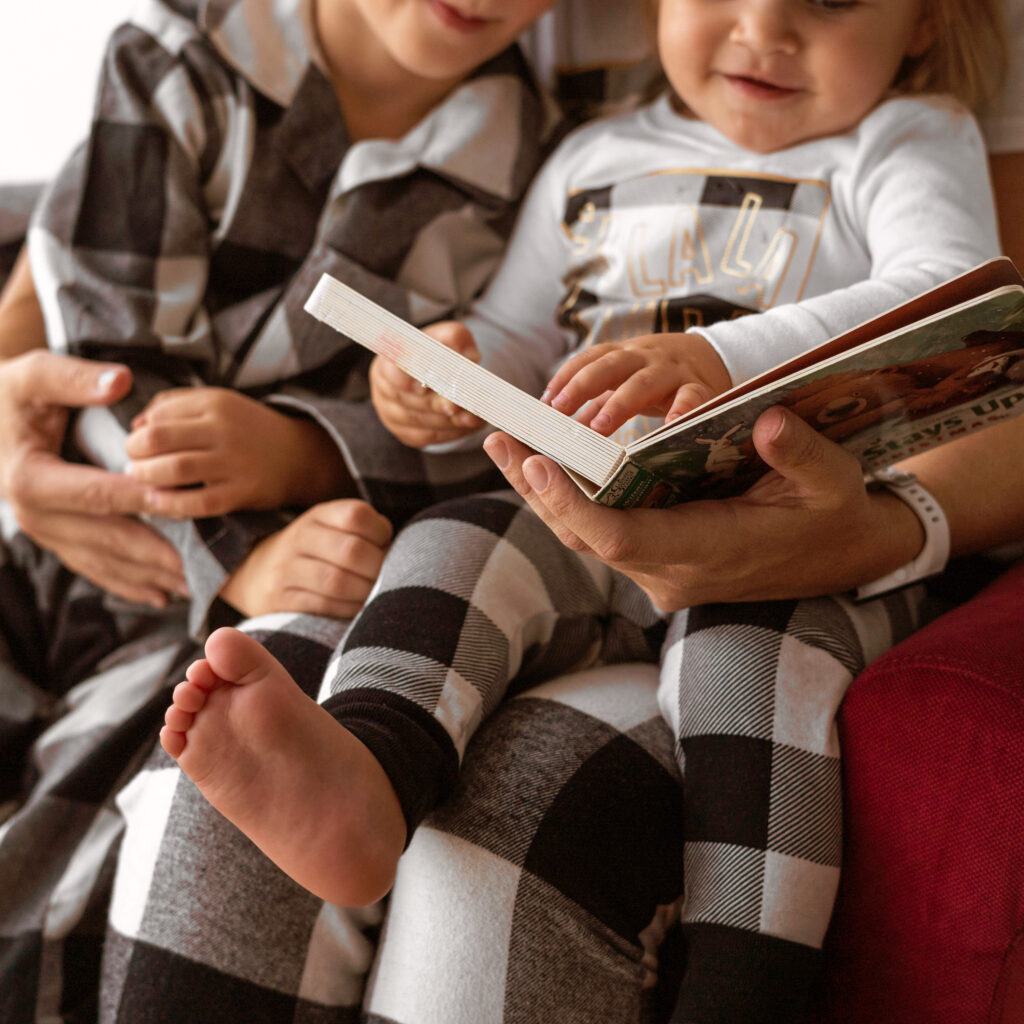 Children and parent quietly reading a book.